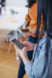 Two women in an office having their phones